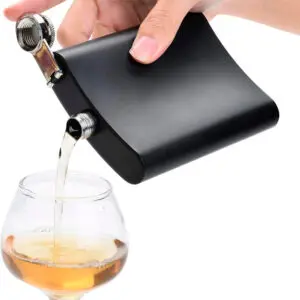 Licorera de acero inoxidable de bolsillo vertiendo whisky en vaso.