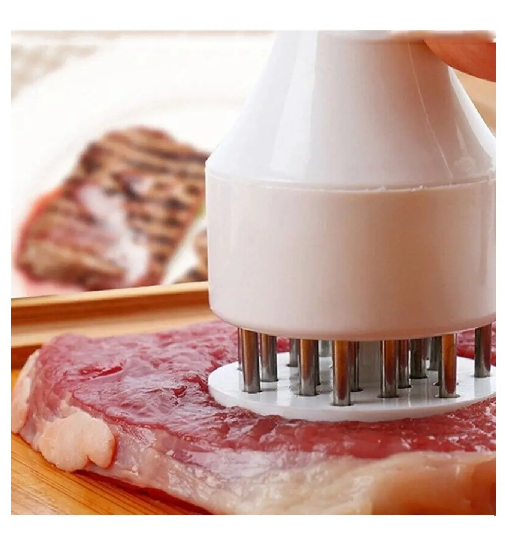 Ablandador de carne con pin de acero inoxidable penetrando en un filete crudo.