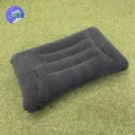Almohada lumbar inflable gris de viaje sobre césped sintético, cojín portátil.