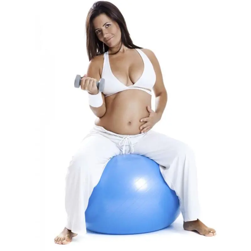 Mujer embarazada hace ejercicio con balón de yoga y pesas, entrenando su cuerpo.