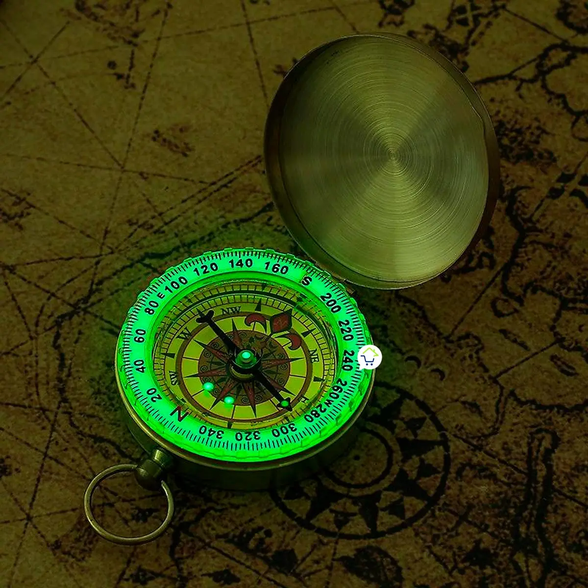 Brújula de bolsillo vintage portátil para campismo, con iluminación verde brillante y tapa abierta sobre mapa.