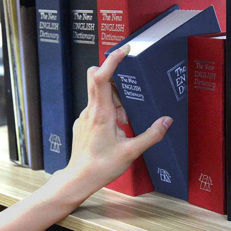 Caja fuerte tipo libro diccionario con mano sacándola de estantería.