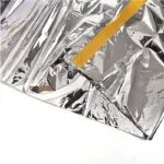 Carpa térmica de camping plateada con borde amarillo, ideal para emergencias y temperaturas extremas.