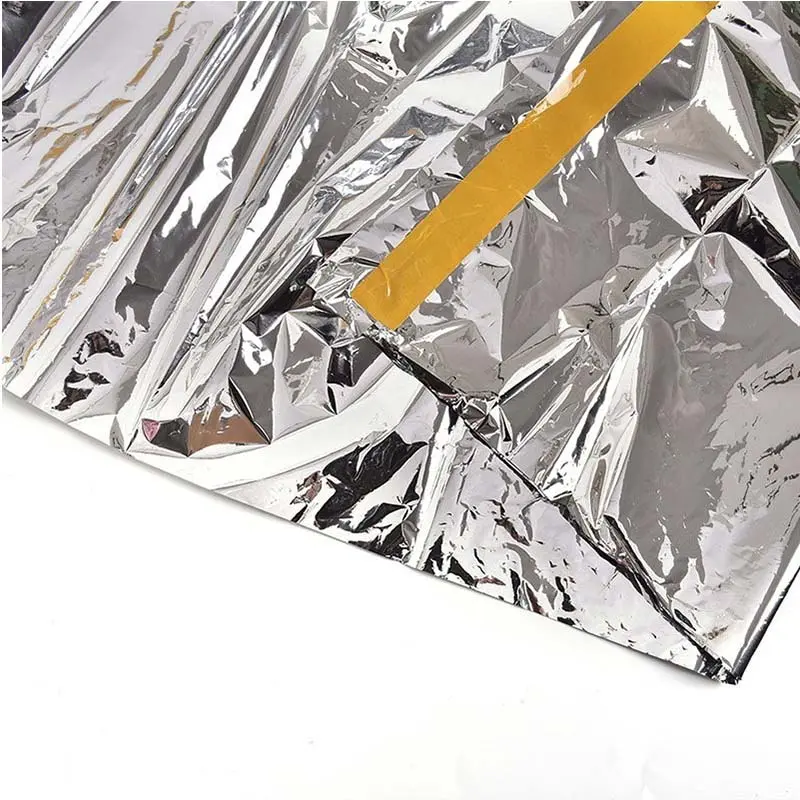 Carpa térmica de camping plateada con borde amarillo, ideal para emergencias y temperaturas extremas.