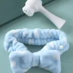 Combo cepillo facial masajeador 2 en 1 y diadema de maquillaje azul con lazo de felpa.