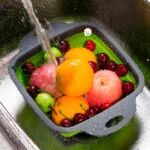 Colador plegable de silicona lavando frutas y verduras en la cocina.