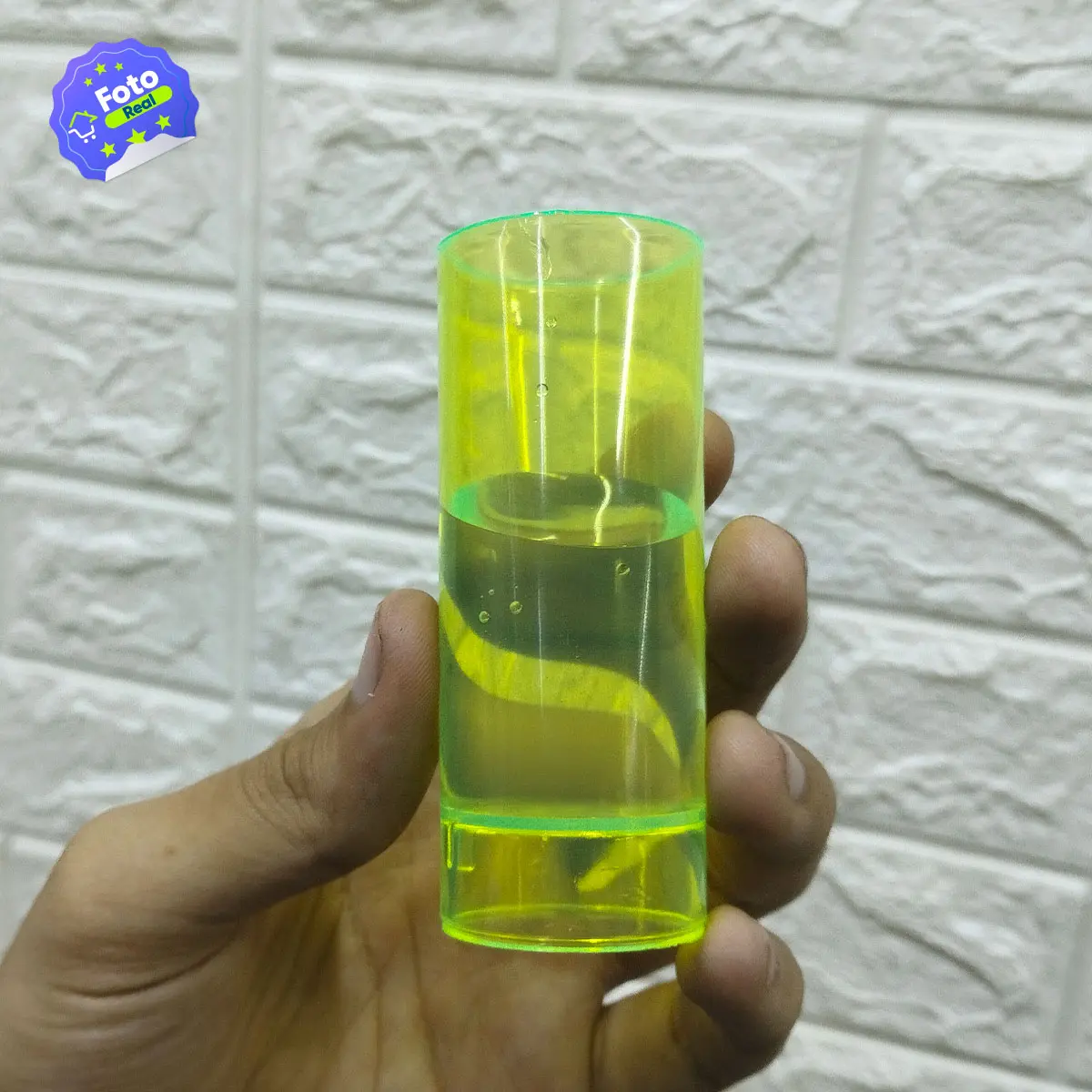 Set x12 copas tequileras neón reutilizables sostenidas en mano, con líquido amarillo brillante.