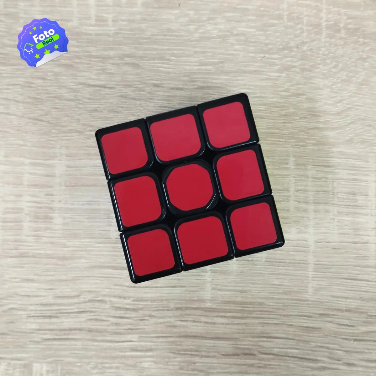 Cubo Rubik 3x3 rojo y negro en mesa de madera con logo " Real".