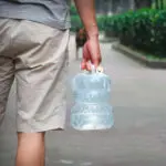 Persona lleva dispensador de agua plegable de 3L, ideal para camping y exteriores.