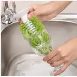 Escobilla lava copas y tazas con ventosa limpiando interior de vaso en lavaplatos.