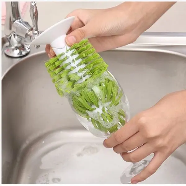 Escobilla lava copas y tazas con ventosa limpiando interior de vaso en lavaplatos.