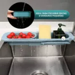Escurridor plegable para cocina con tomates, esponja y dispensador de jabón sobre lavaplatos.