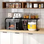 Estante organizador para horno microondas, repisa con electrodomésticos y frascos de cocina.