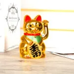 Gato de la suerte dorado Maneki Neko móvil, figura decorativa de la fortuna sobre mesa de madera.