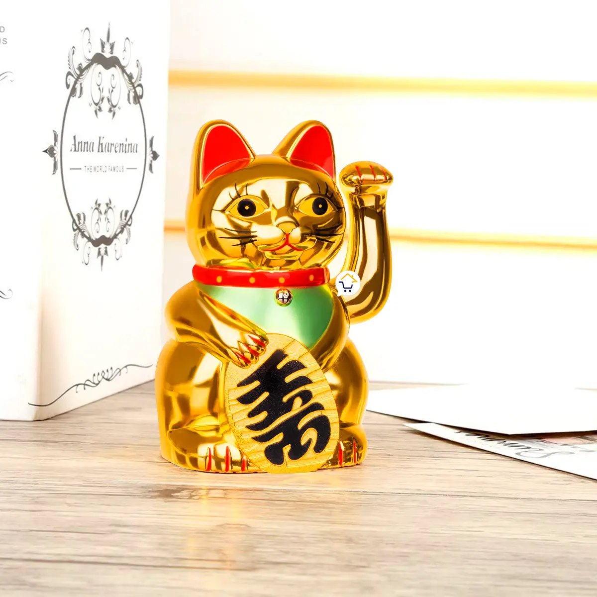 Gato de la suerte dorado Maneki Neko móvil, figura decorativa de la fortuna sobre mesa de madera.
