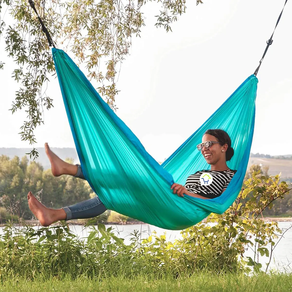 Mujer sonriendo en hamaca azul turquesa para camping, ligera y portátil.