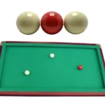 Juego de billar de carambola de 3 bandas con 3 bolas (2 blancas, 1 roja) en mesa verde.