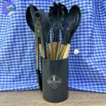 Juego de 12 utensilios de cocina de silicona resistentes al calor en organizador gris con fondo de cuadros azules.