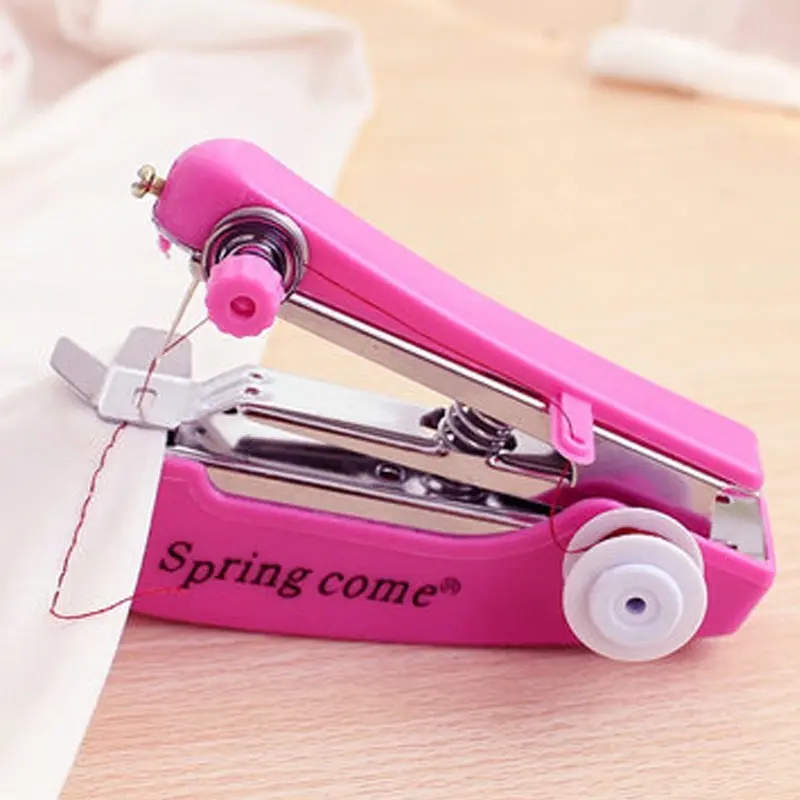 Mini máquina de coser de mano portátil rosa cosiendo tela blanca con hilo rojo.