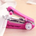 Mini máquina de coser de mano portátil rosa con hilo rojo cosiendo tela blanca.