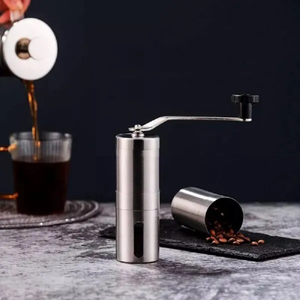 Molino de café manual de acero inoxidable con manivela y recipiente para granos.