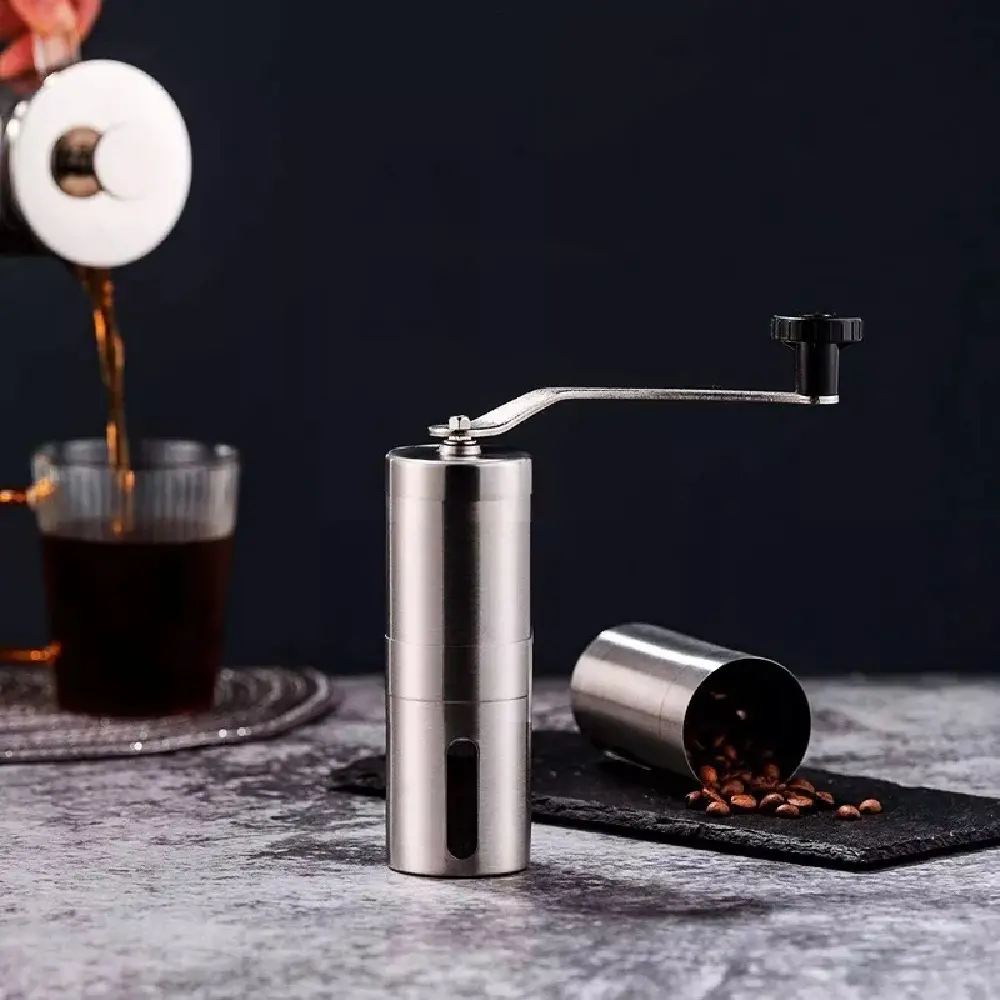 Molino de café manual de acero inoxidable con manivela y recipiente para granos.
