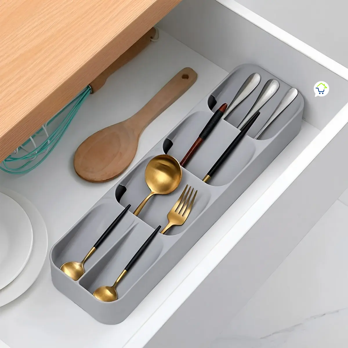 Organizador de cubiertos dorado y plateado en cajón de cocina con utensilios de madera y batidor.