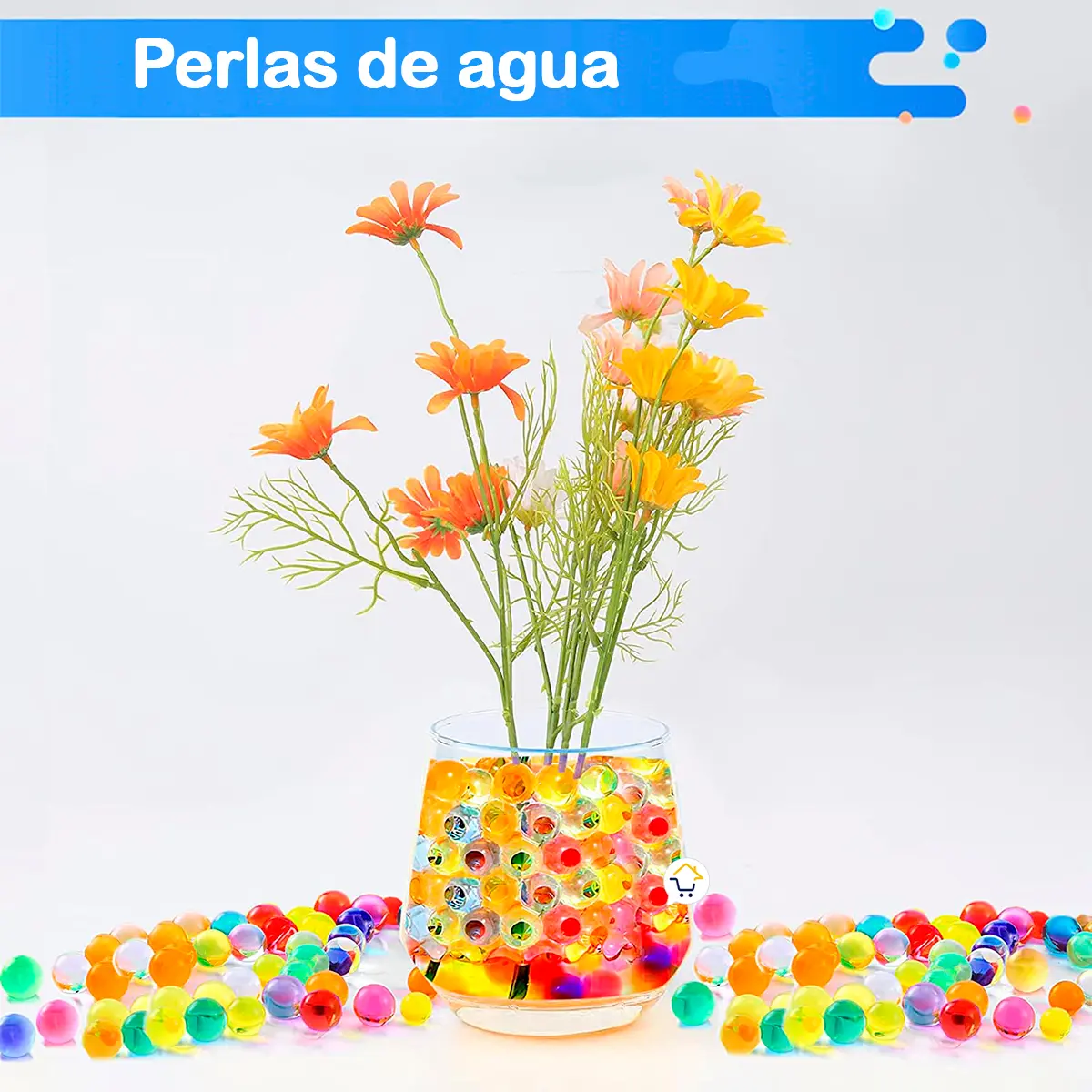 Perlas de hidrogel coloridas para decoración, en vaso con flores y esparcidas sobre superficie blanca.