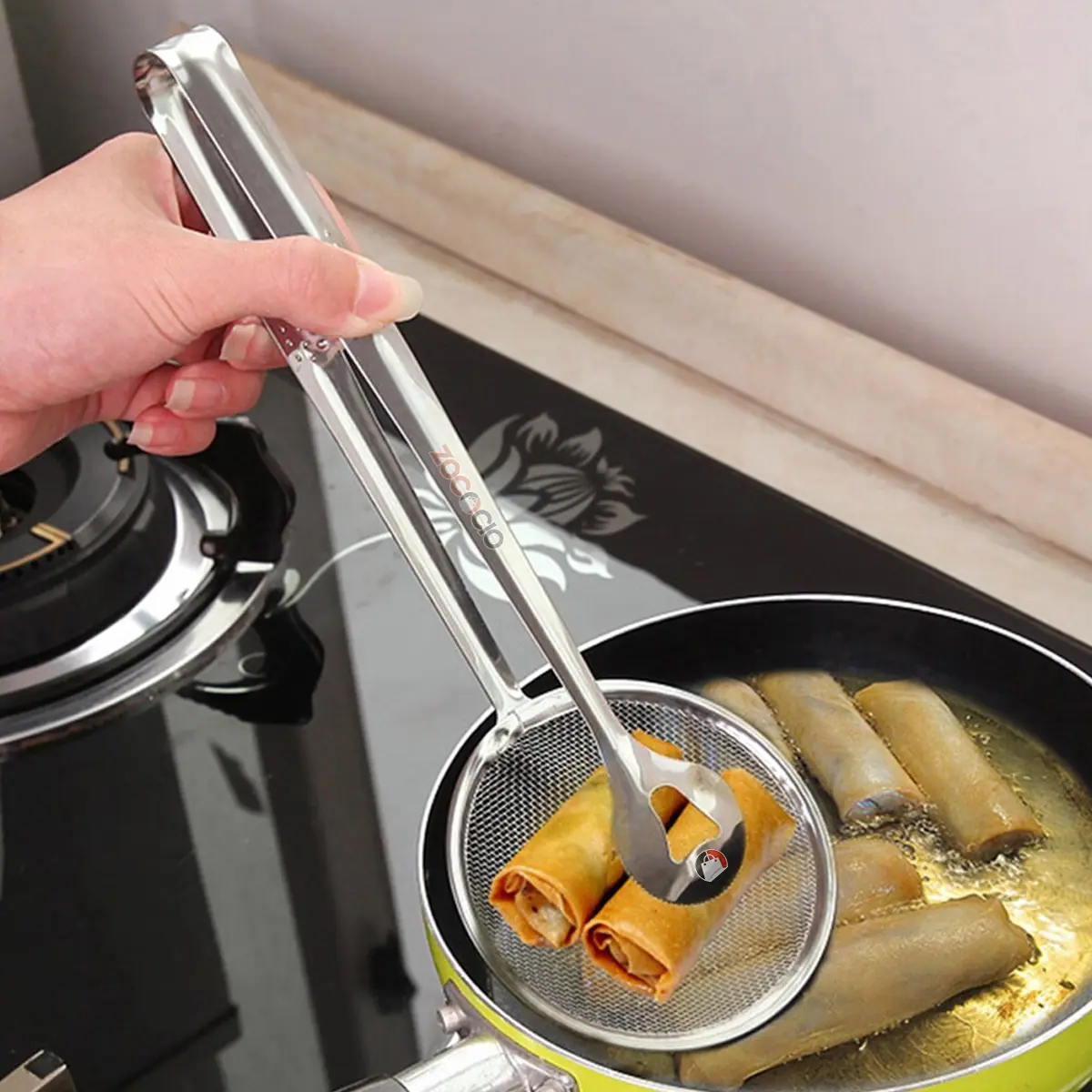 Pinza colador de cocina con resorte y cuchara para freír, ideal para sacar alimentos del aceite caliente.