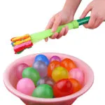 Set x2 Recargador de Globos de Agua Magic Balloons, manos llenando globos coloridos en tina rosa.