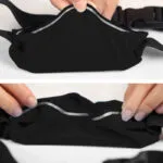 Riñonera deportiva negra impermeable para celular con detalles reflectantes, vista cercana.