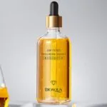 Serum Bioaqua 24K Gold Hyaluronic Essence con gotas doradas en frasco de vidrio transparente.