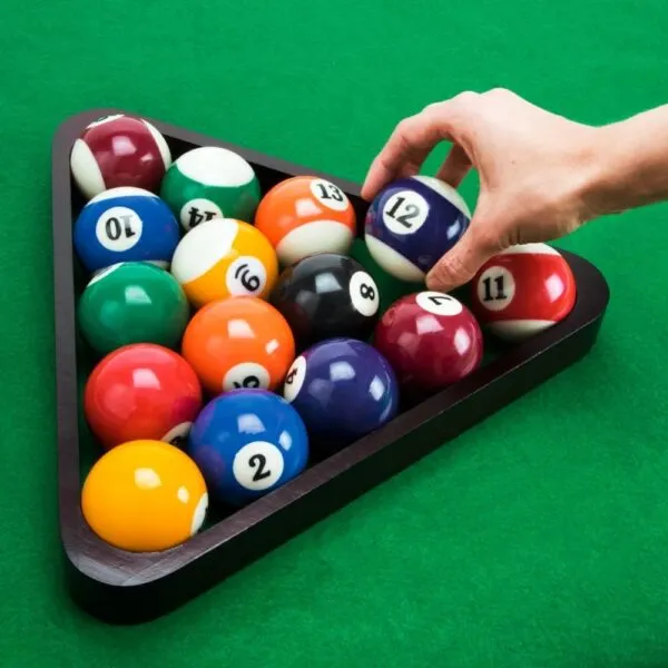 Set de 16 bolas de billar para pool, con mano colocando bola #12 en el triángulo.