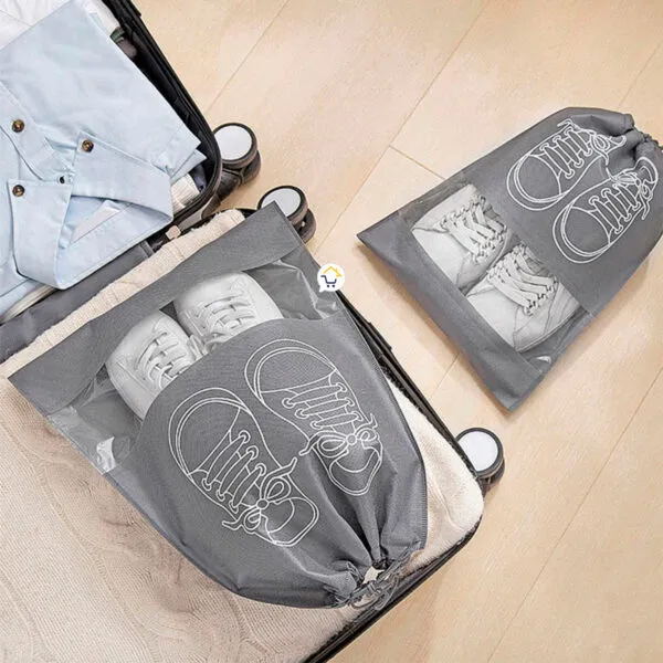Set x4 bolsas organizadoras de zapatos anti-polvo grises con zapatillas blancas en un suitcase.