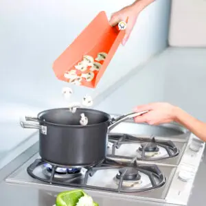 Tabla plegable vierte champiñones picados en olla sobre estufa mientras se cocina.