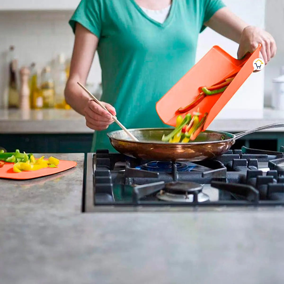 Tabla de cortar plegable volcando pimientos en sartén sobre estufa, cocina casera.