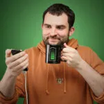 Hombre sostiene celular y taza mágica que cambia con el calor, con diseño de batería.