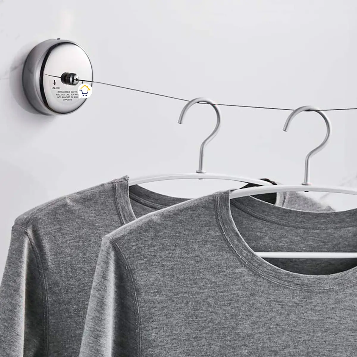 Tendedero retráctil de pared ajustable con dos camisetas grises colgadas.