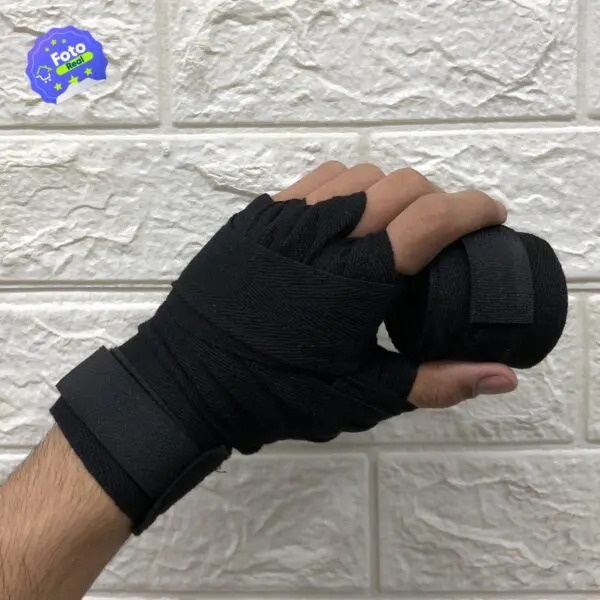 Mano con vendas de boxeo negras para entrenamiento de deportes de contacto, asegurando muñeca y puño.