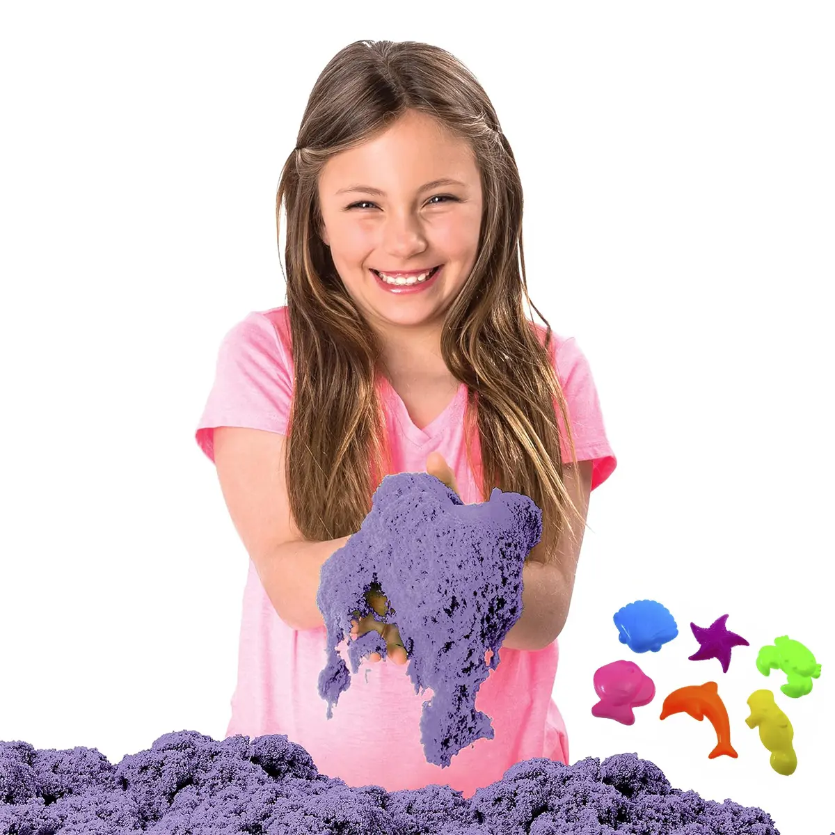 Niña sonriente jugando con arena cinética morada y moldes de playa.
