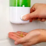 Dispensador de jabón dosificador antibacterial, vertiendo líquido en mano.
