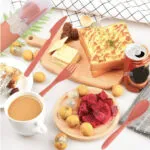 Juego de cubiertos viajeros con estuche, pan tostado, frutas y lata de refresco para un picnic.