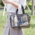 Cartera cosmetiquera transparente con logo y neceser, ideal para viajes.