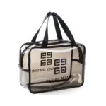 Bolso cosmetiquera transparente con logo y asas negras, ideal para viajes.