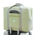 Maleta plegable de viaje impermeable color verde menta con asa de mano sobre equipaje.