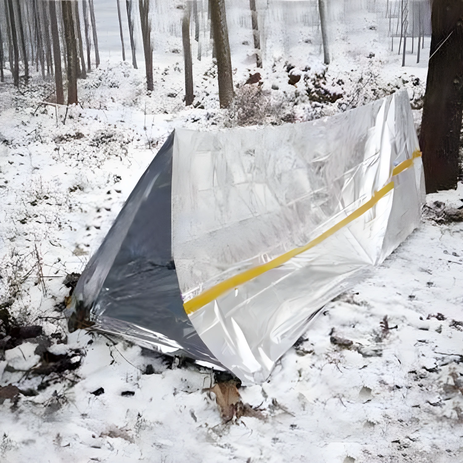 Carpa térmica de emergencia plateada y amarilla para camping en bosque nevado.