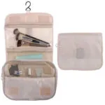 Cosmetiquera colgante beige para viajes con organizador de brochas y compartimentos de malla.