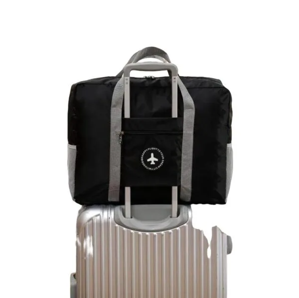 Maleta plegable de viaje impermeable negra con asas grises sobre maleta plateada.