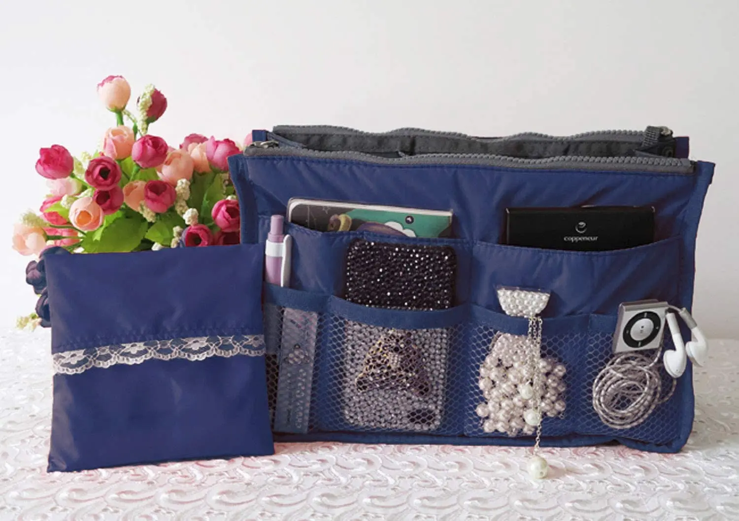 Organizador expandible azul para bolsos y maletas de dama, con accesorios y flores.