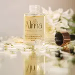 Tónico facial Alma despigmentante e iluminador en frasco de vidrio con gotero sobre pétalos.